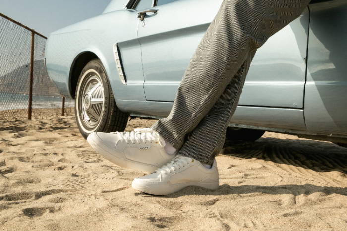 Male model legs leaning on car wearing wearing Levi's 521 XX EST Lo leather sneakers 