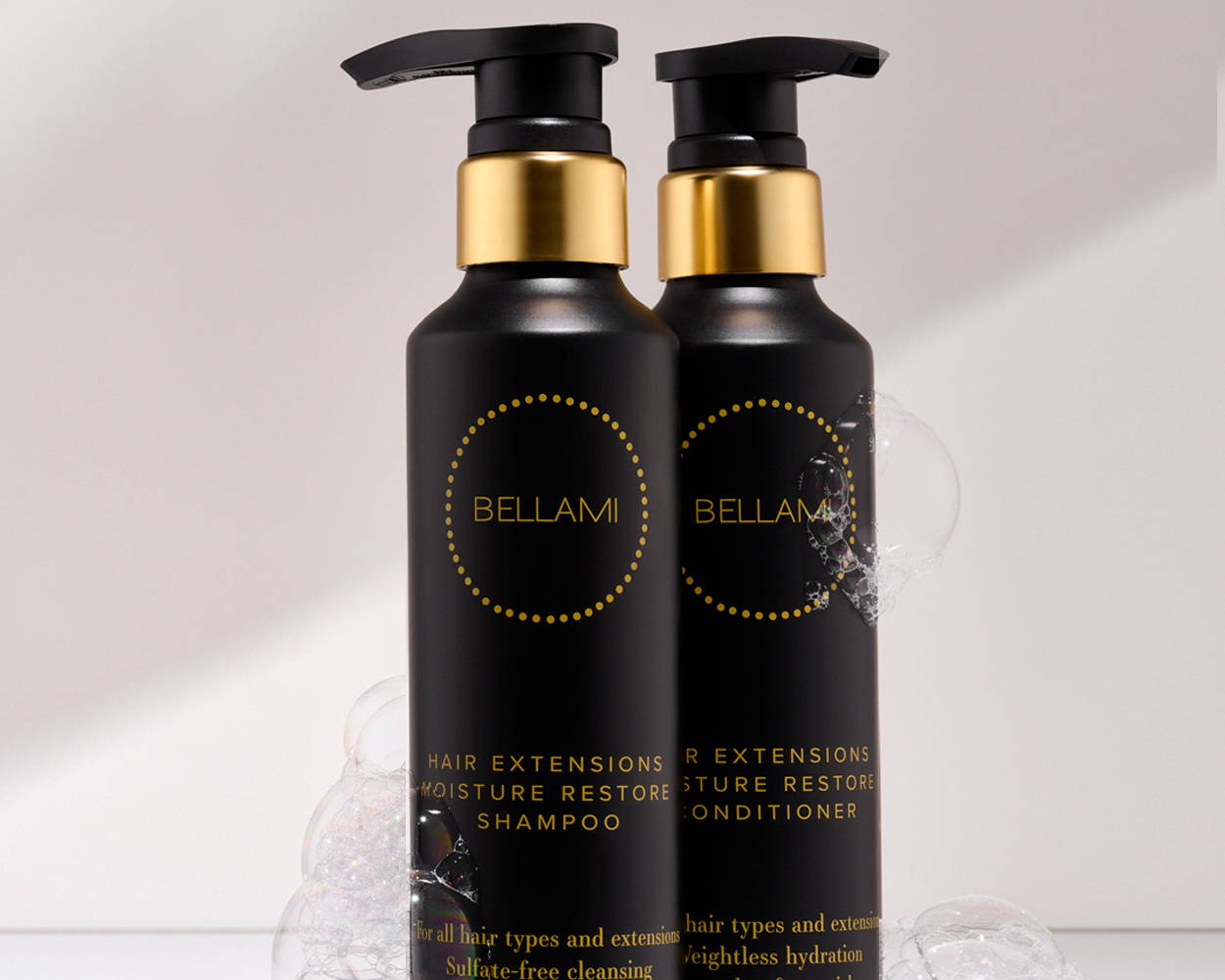 Two Bellami shampoo and conditioner bottles with black and gold packaging, surrounded by bubbles.