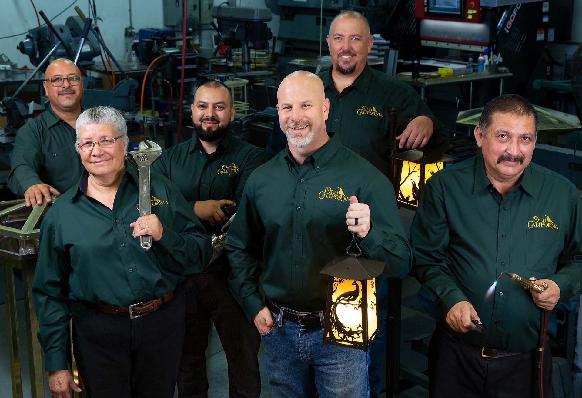 A portrait of six employees of Old California. They are in a factory and all wearing green shirts.