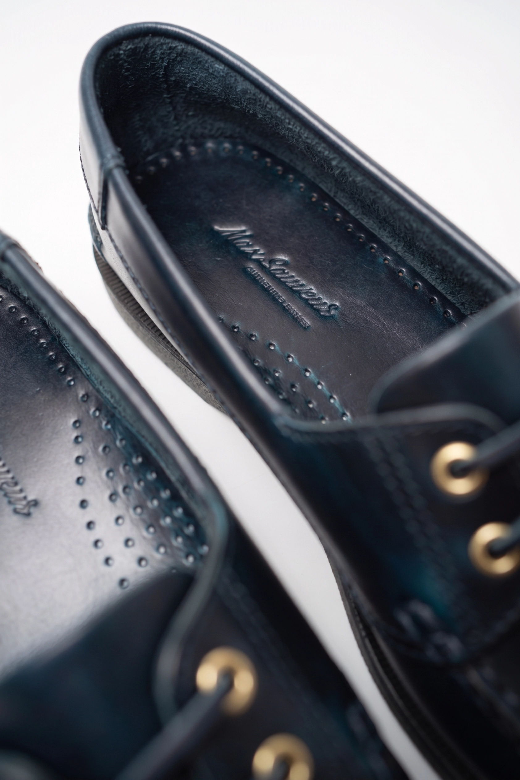 Close-up of black shoes with gold eyelets and perforated insoles.