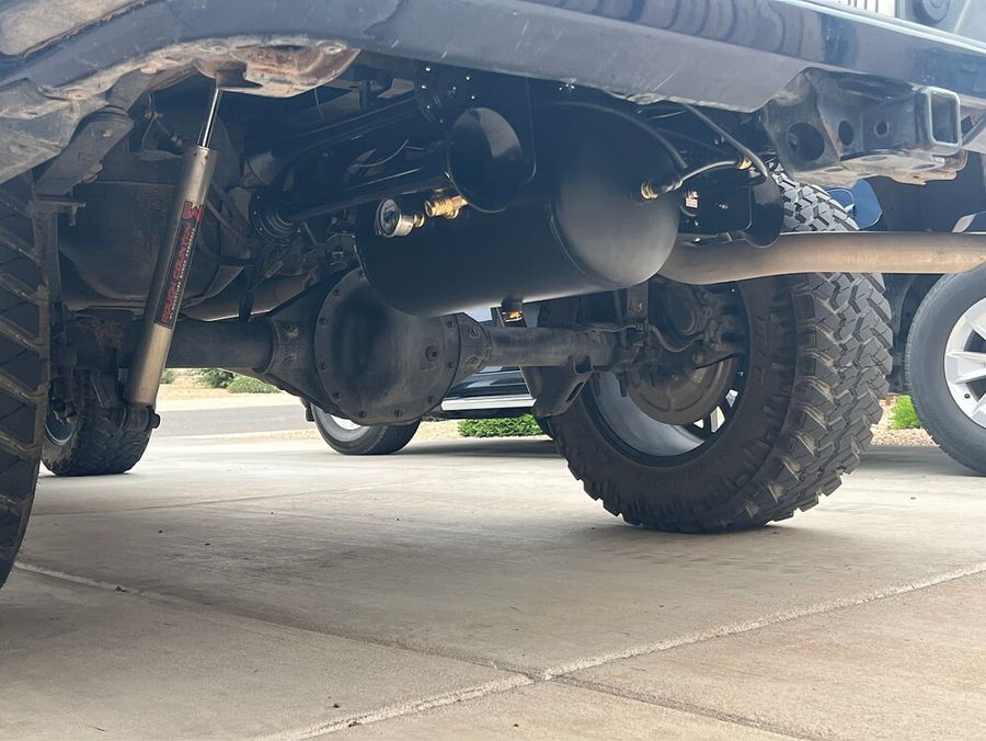 Rear undercarriage view matte black air tank train horns pressure gauge and Rough Country shock Stealth Spare Tire Delete install Brian's 2022 Chevy Silverado gallery photo 3