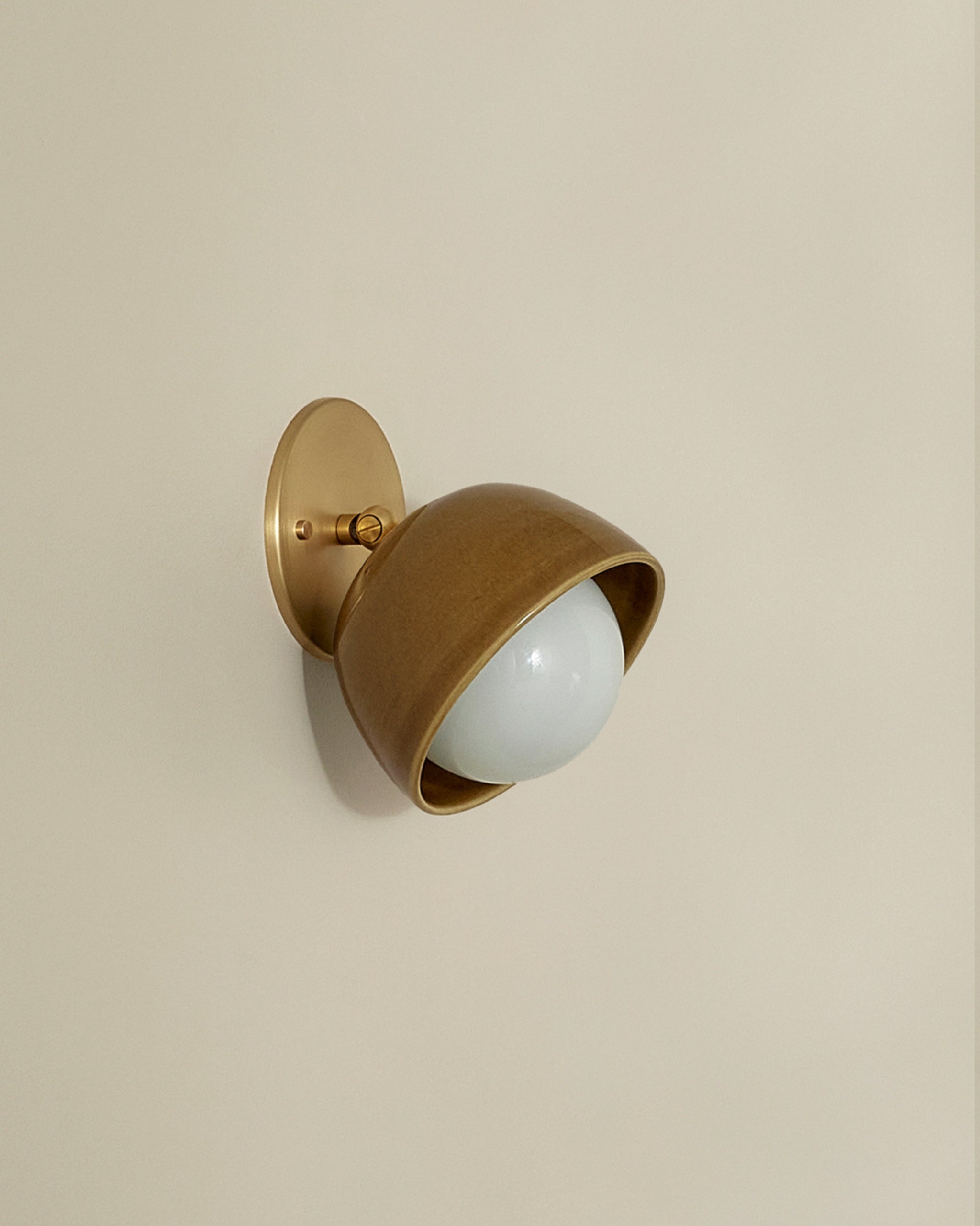 Brass wall-mounted light fixture on a beige wall