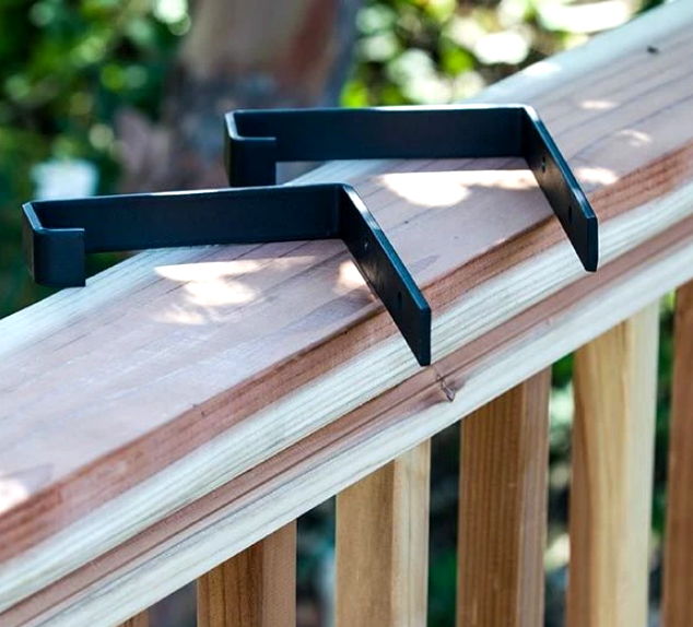 Two black brackets resting on a wooden railing.