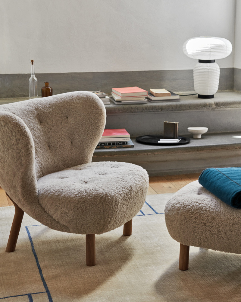 A cozy, textured &Tradition armchair with wooden legs and button details.
