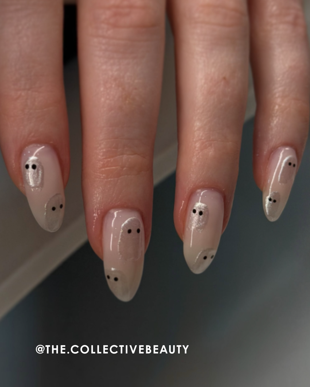 Manicure with nude polish and black dot designs on long, pointed nails.