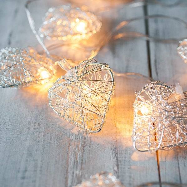 Heart fairy lights with a warm white glow on a wooden table.