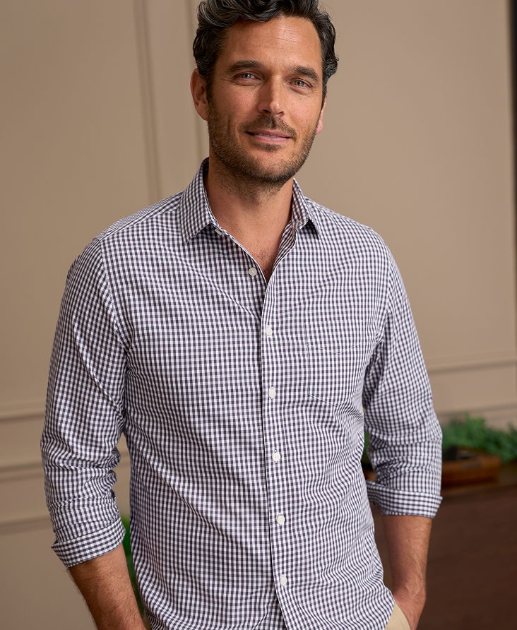 Man in a checkered shirt standing with a neutral background.