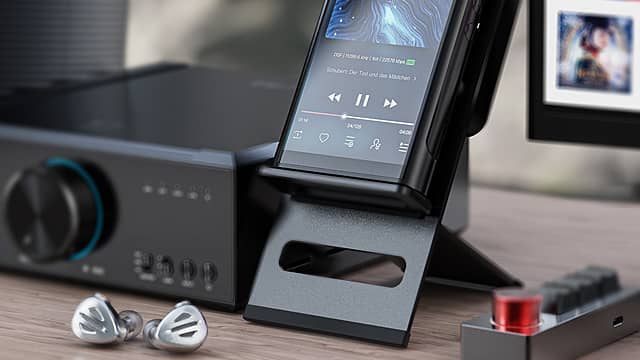 A hi-res audio player on a stand next to audio equipment and headphones.