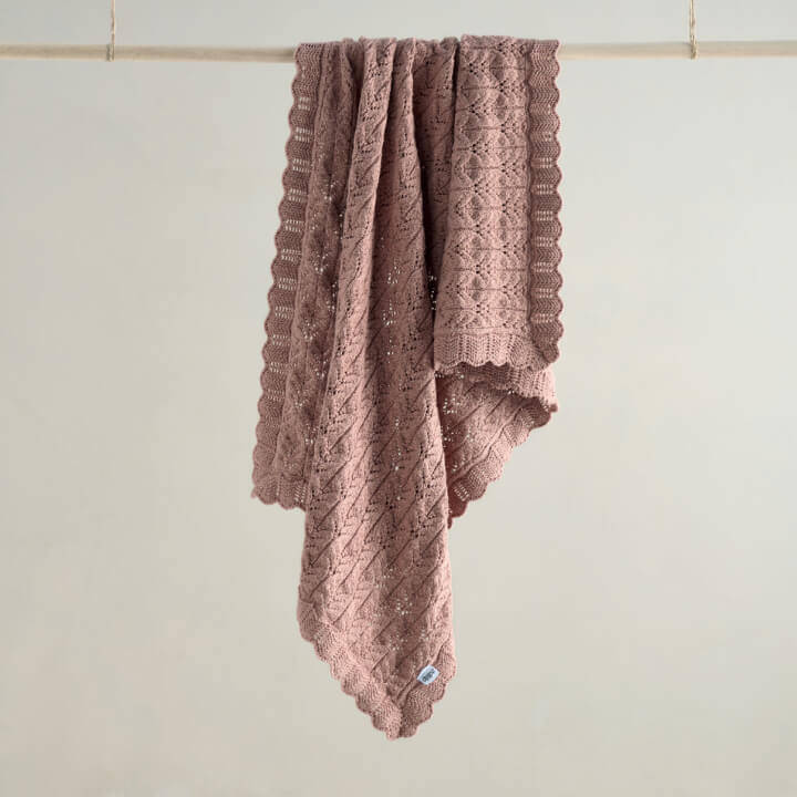 A soft, pink textured blanket hanging on a clothesline.