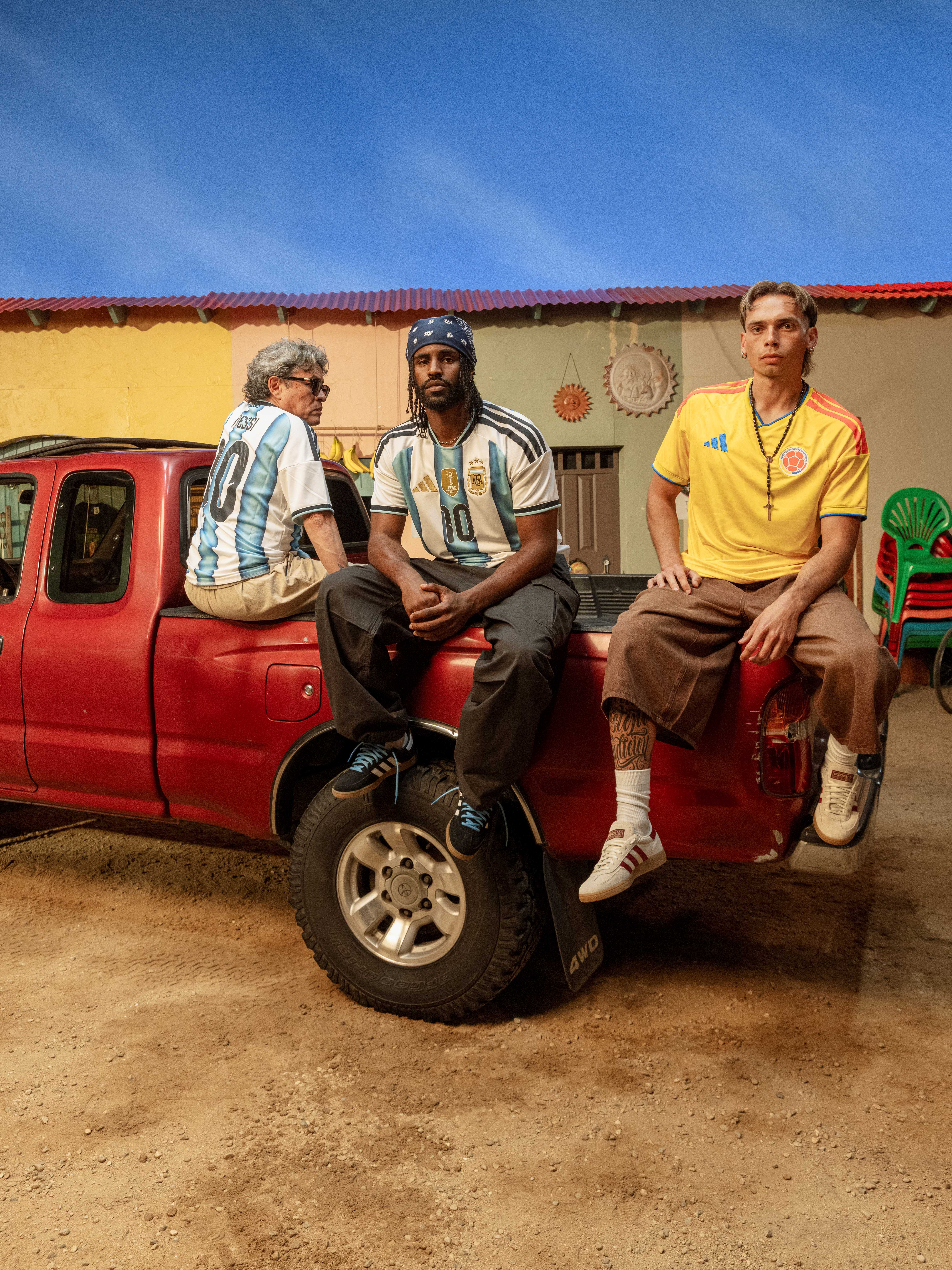 Three men in sports jerseys sitting on a red truck.