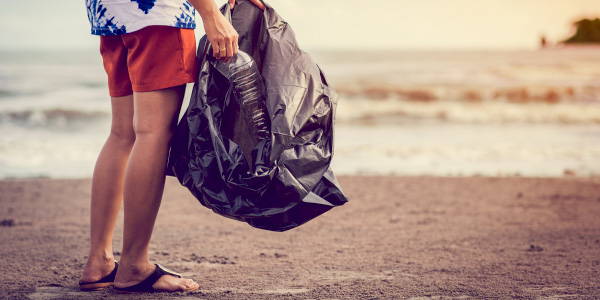 Mensch mit Mülltüte am Strand