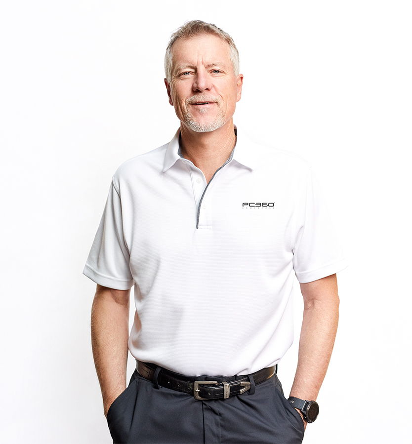 Man in a white polo shirt standing with hands in pockets against a white background.