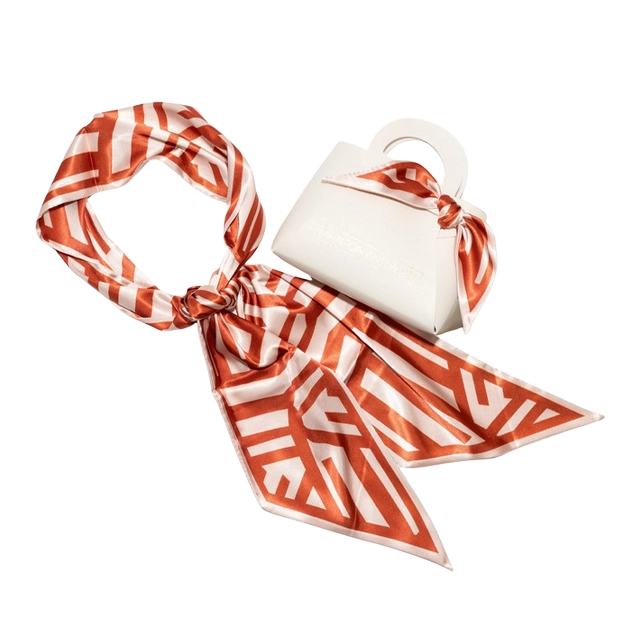 White handbag with orange patterned scarf.