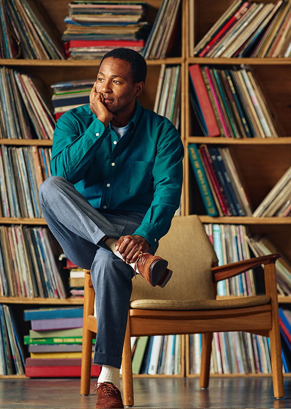 Man sitting in a chair, surrounded by shelves of records.