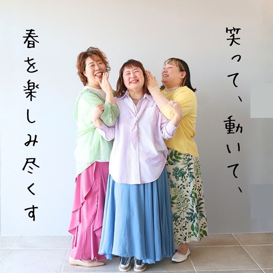 Three women in colorful outfits, smiling and posing together.