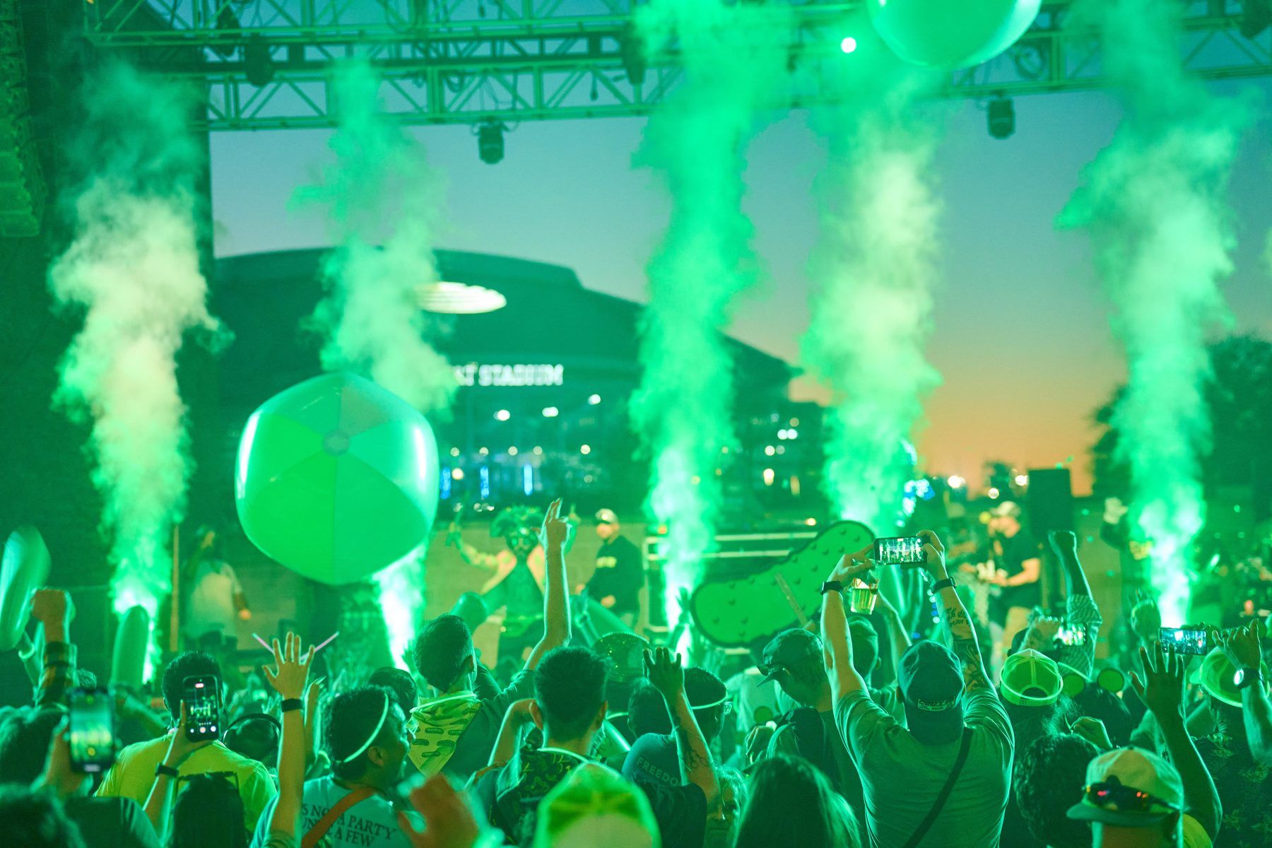 Crowd at the Pickle RAVE with green CO2 jets and giant inflatable pickle at The Big Dill, AT&T Stadium in the background, Arlington Texas 2025.