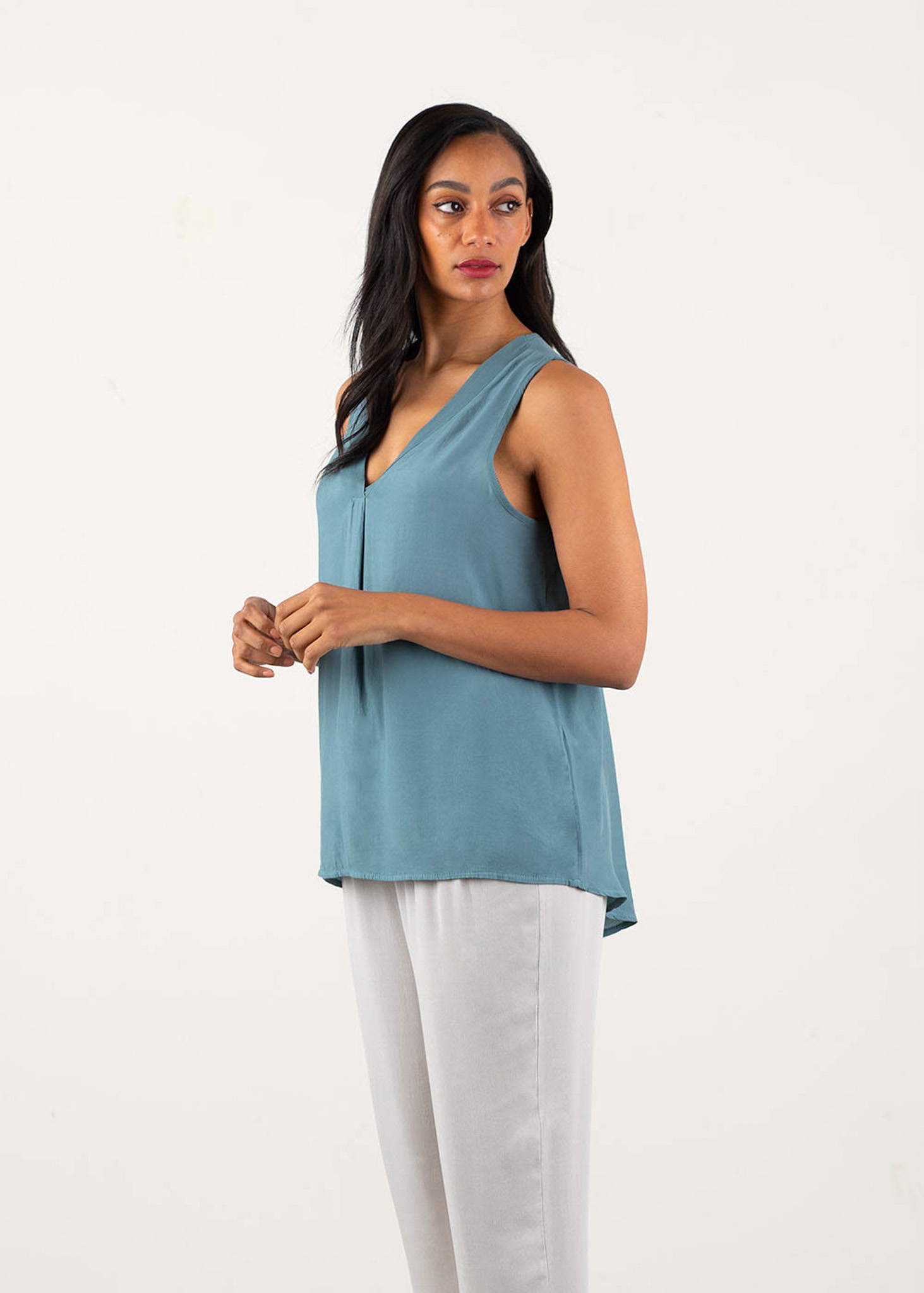 A model wearing a blue grey v-neck, sleeveless top over oatmeal drapey trouser and cream block heels