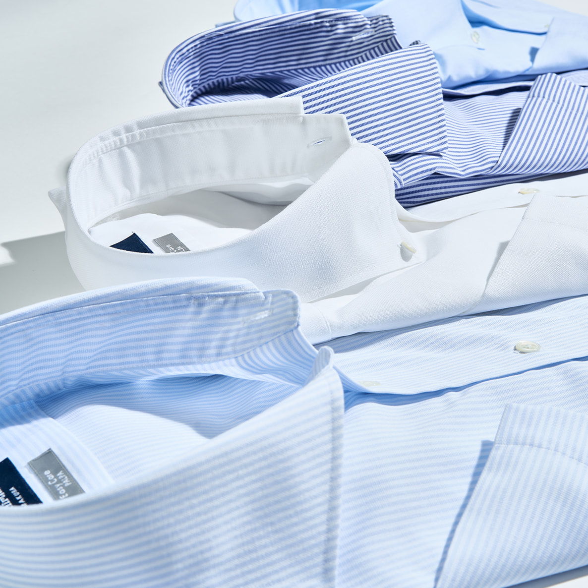 Collared dress shirts in various shades of blue and white, neatly arranged.