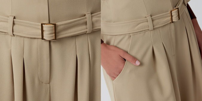 Close-up of khaki pants with pleats and a hand in the pocket.