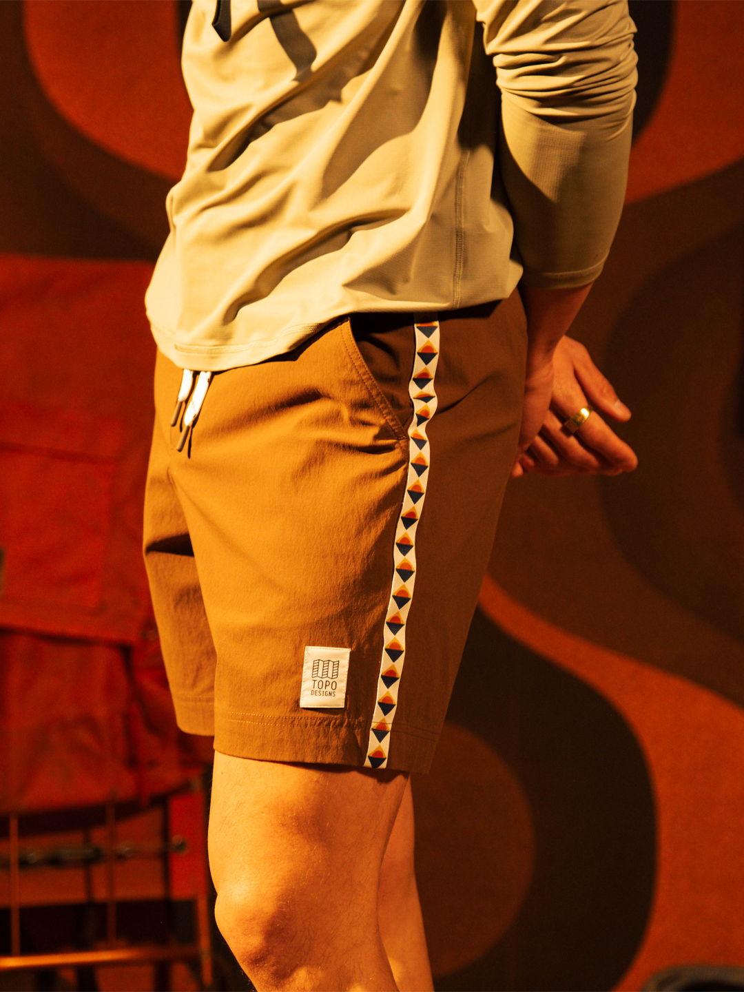 Person wearing brown shorts with a decorative side stripe.