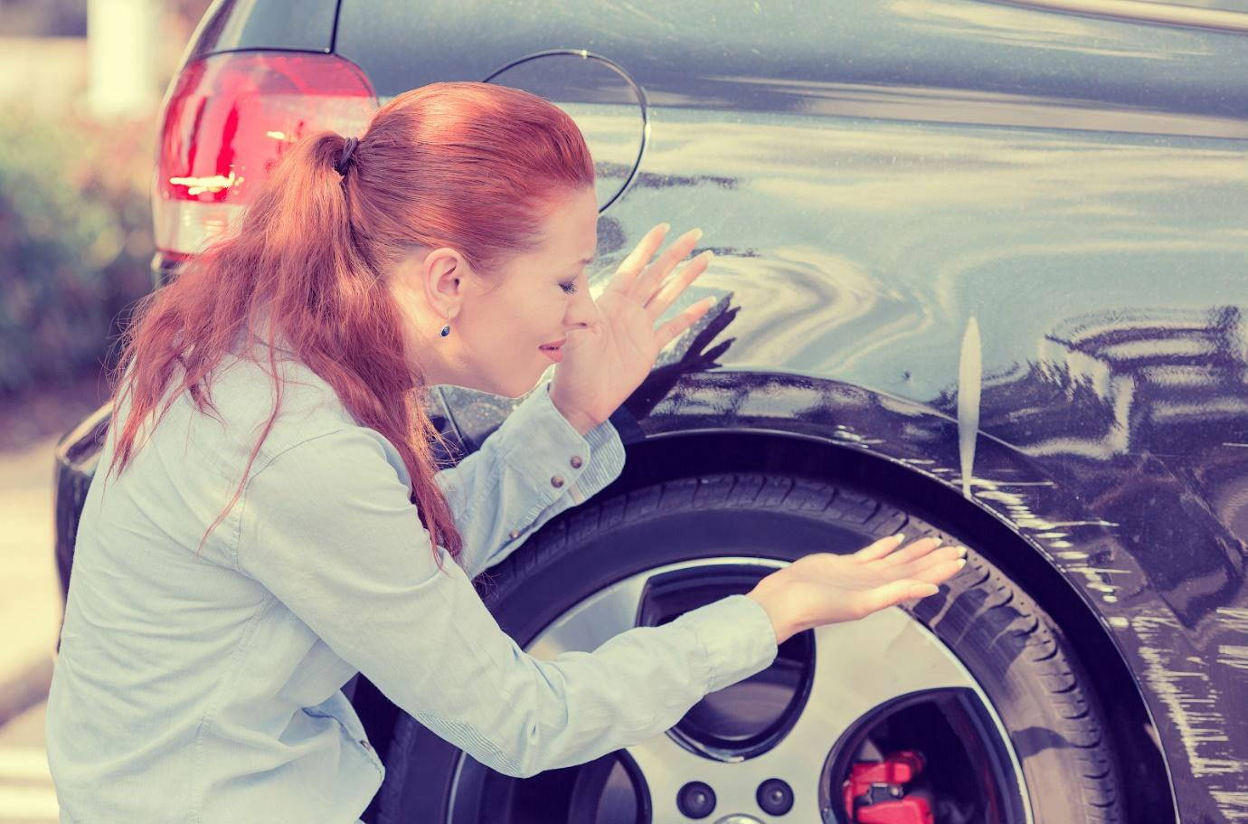  A woman observing deep scratches on her car’s paint