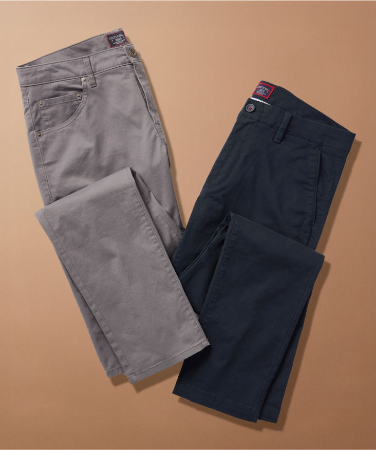 Two pairs of pants in gray and navy laid on a brown background.