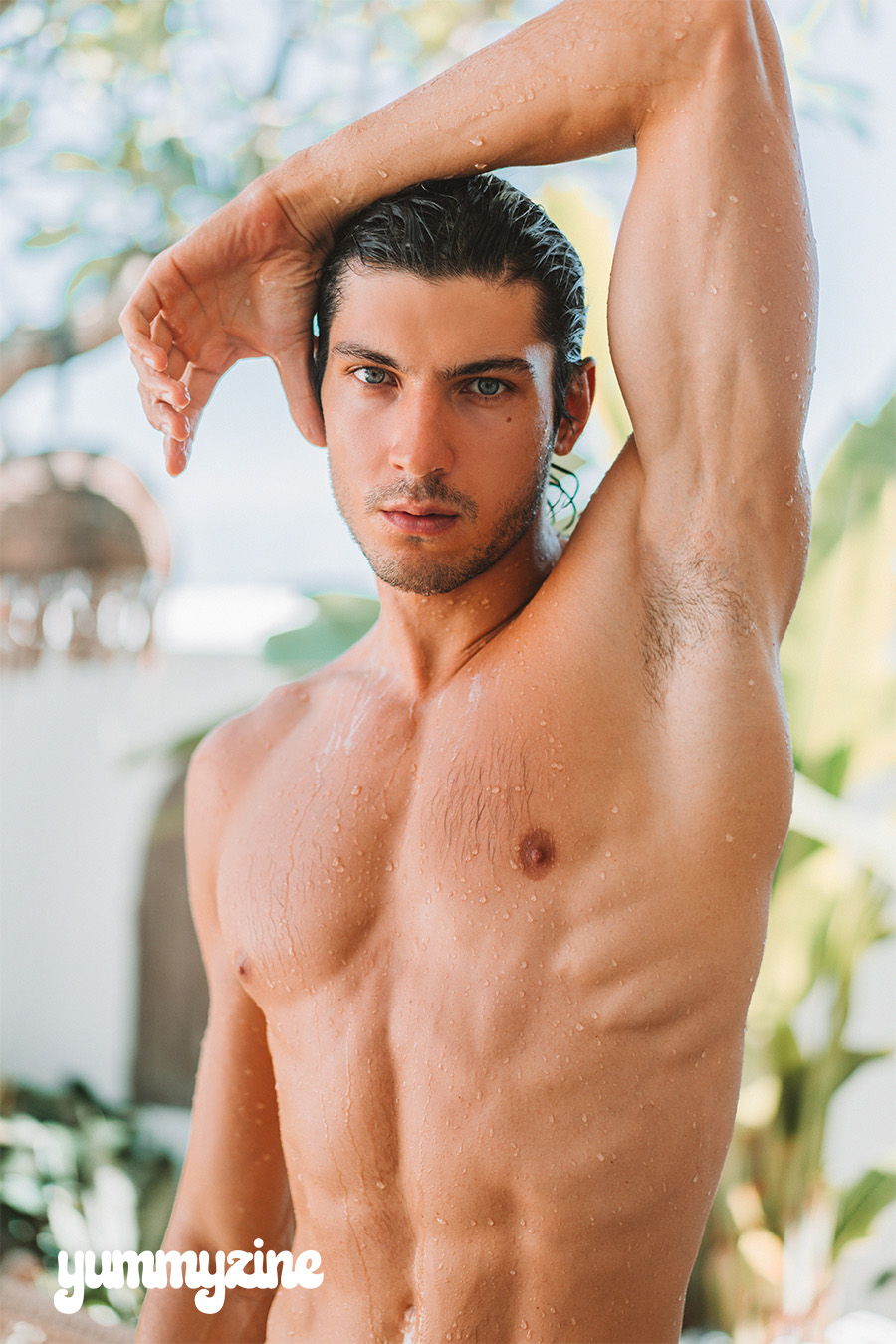 A muscular young man posing outdoors with a confident expression.