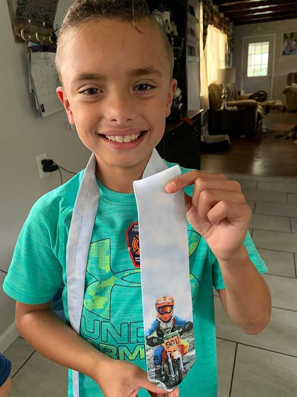 Child holding a custom tie with his photo