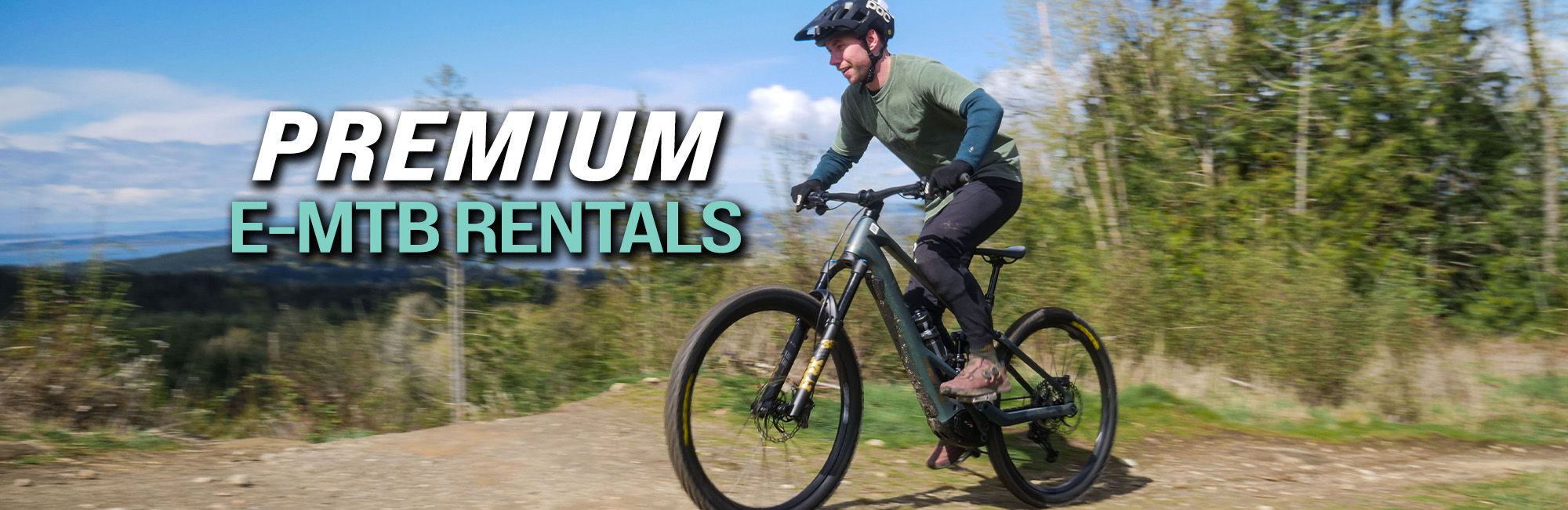 Person riding a mountain bike with trees and sky in the background.