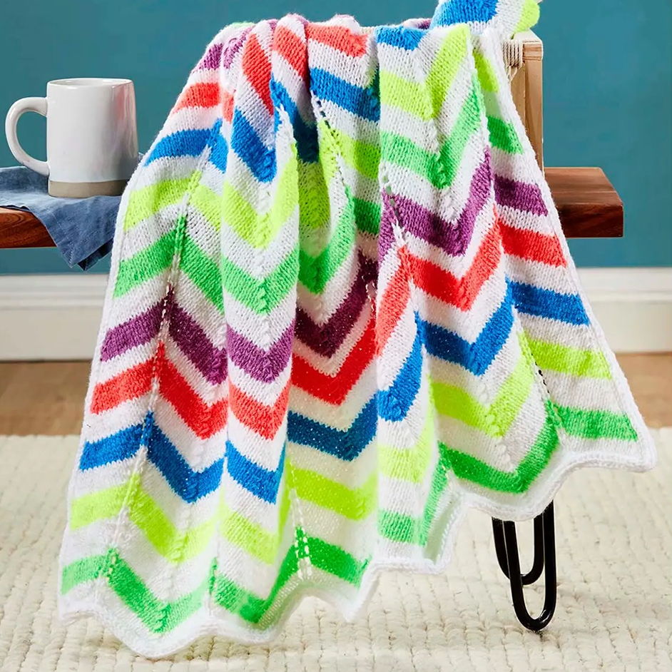 Colorful chevron-patterned blanket draped over a chair with a mug nearby.