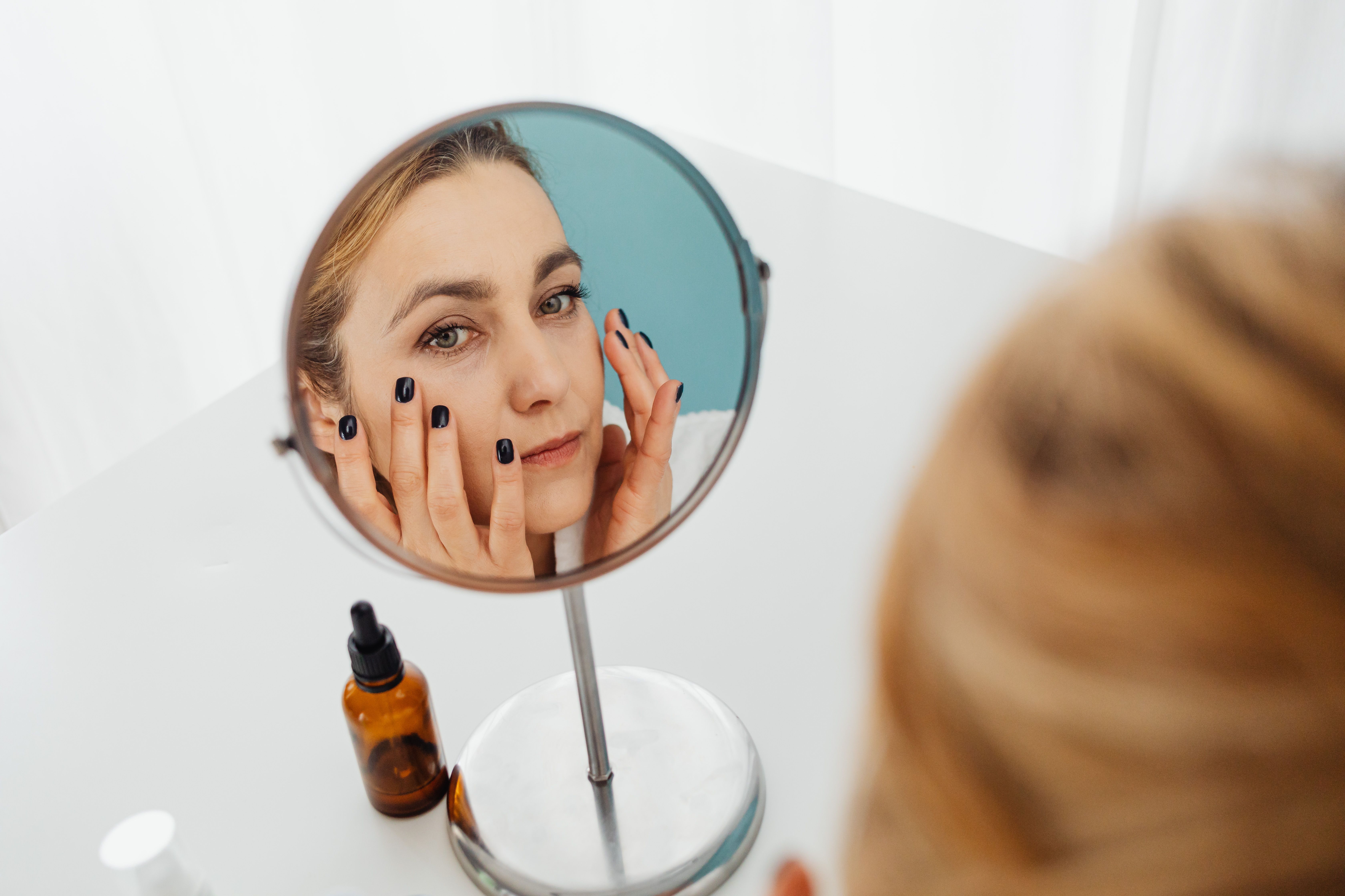 Person applying skincare while looking in a mirror.