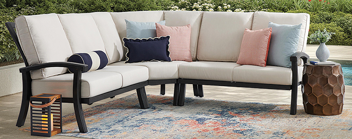 Outdoor sectional sofa with colorful pillows and a decorative rug.