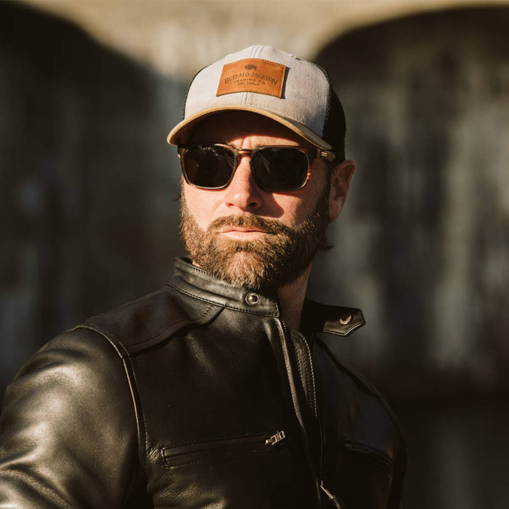 man wearing black leather moto jacket with sunglasses and trucker hat