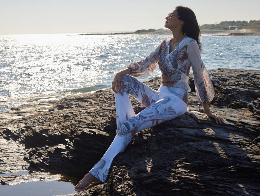 Woman wearing shell printed cotton wrap top with matching brown and white pants on the rocks by the ocean in Newport Rhode Island by Ala von Auersperg