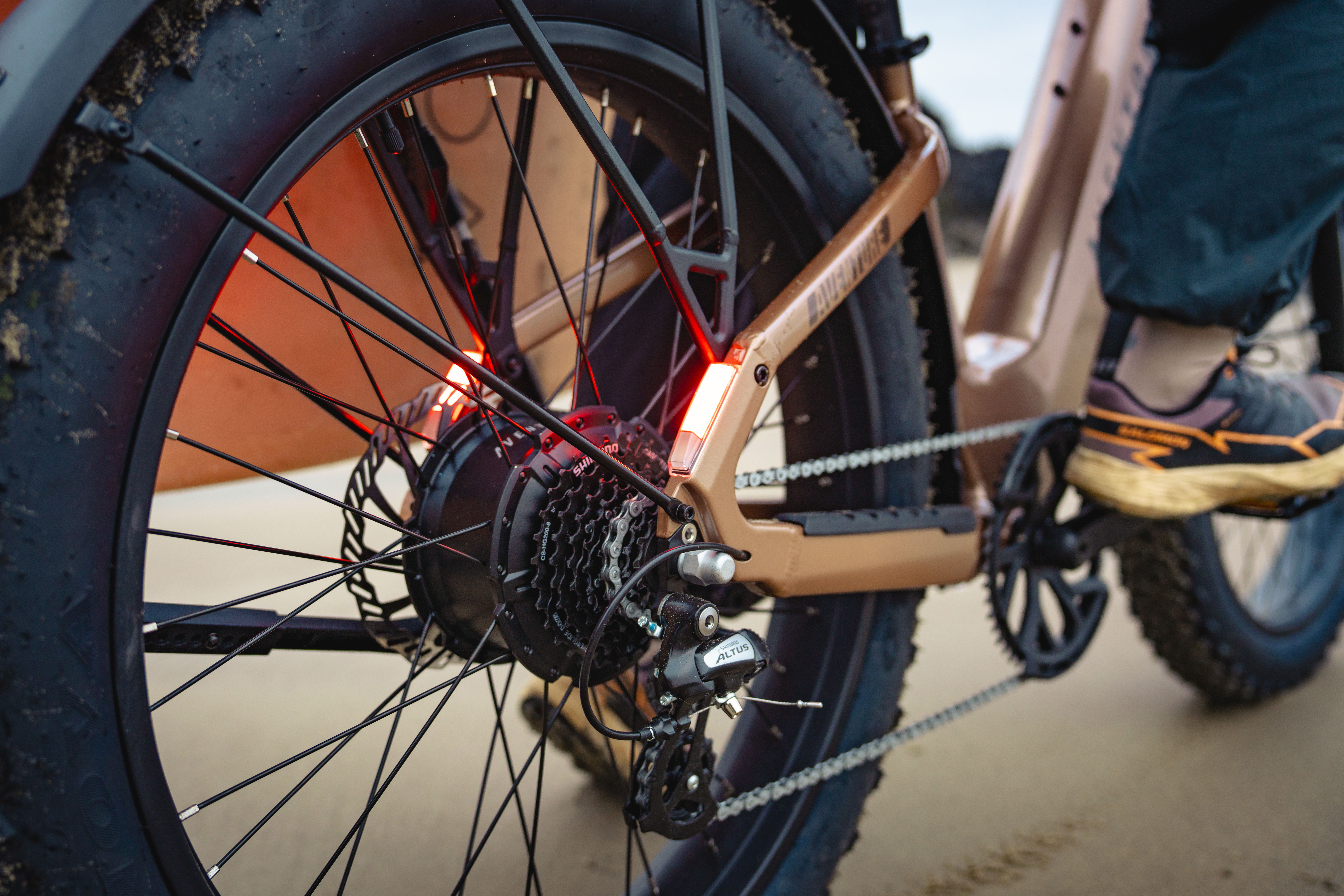 Close-up of a bicycle wheel with a red light and a rider's foot.