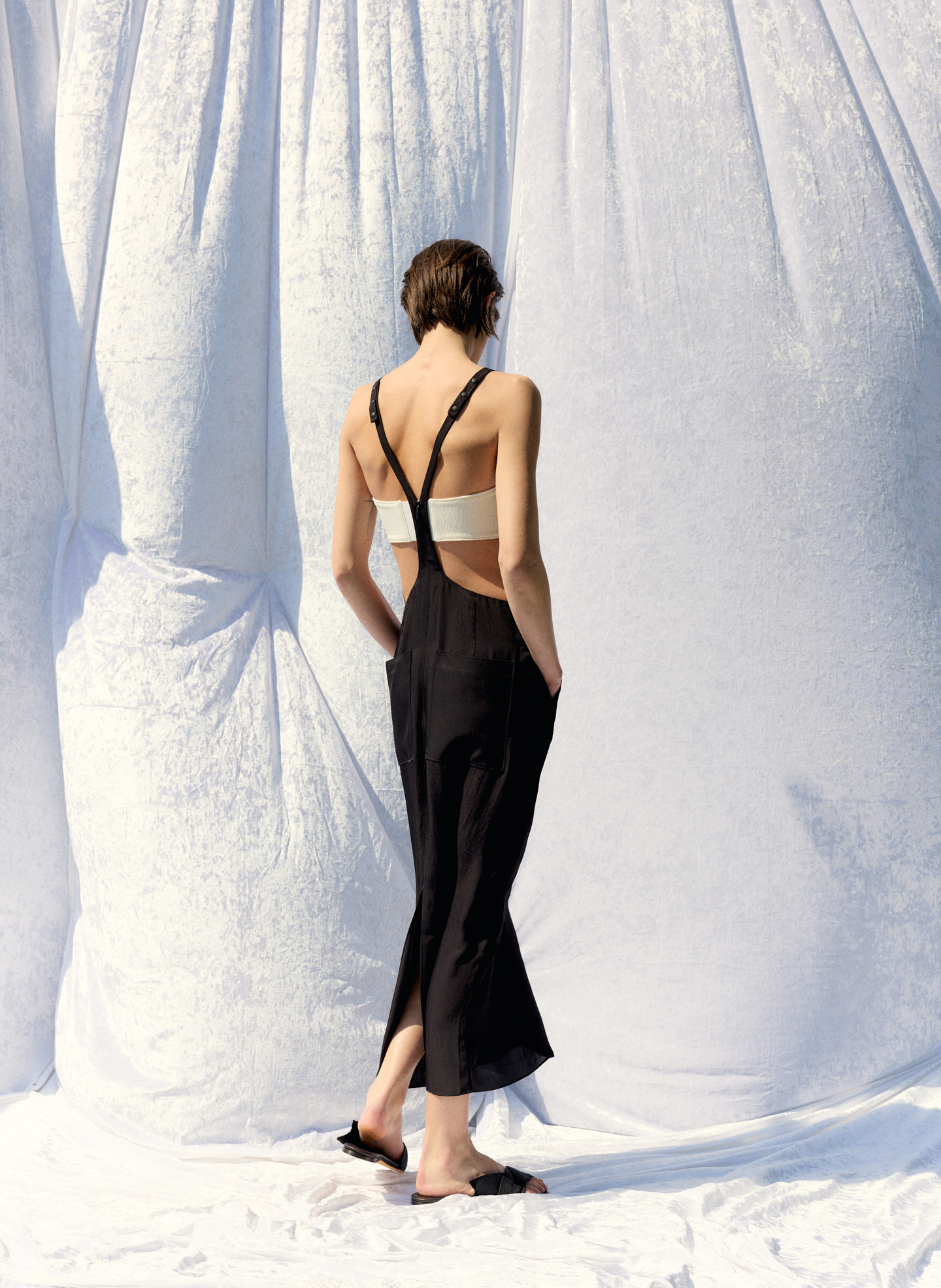 A woman in a black dress poses against a white backdrop.