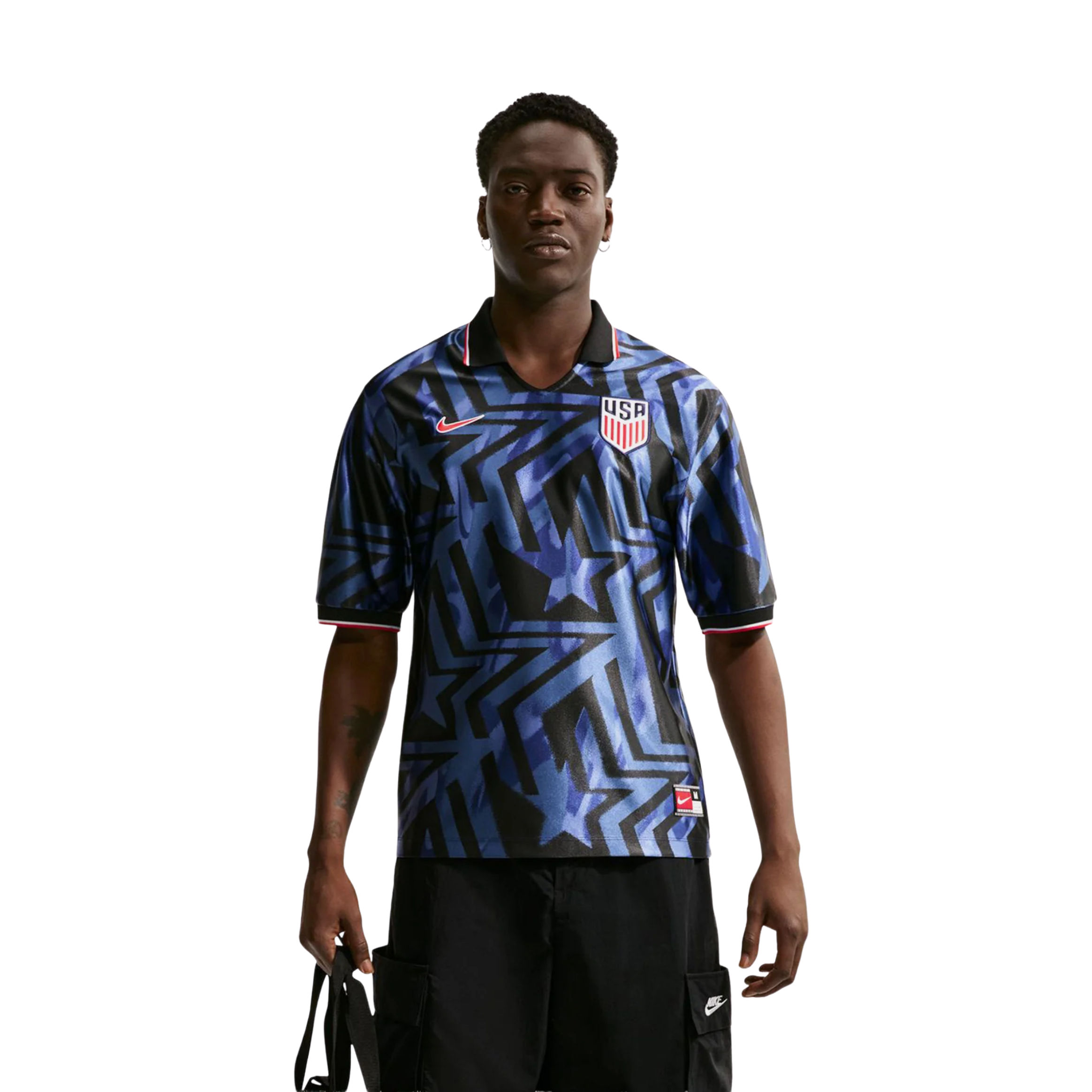 Person wearing a blue patterned jersey and black shorts, standing confidently.