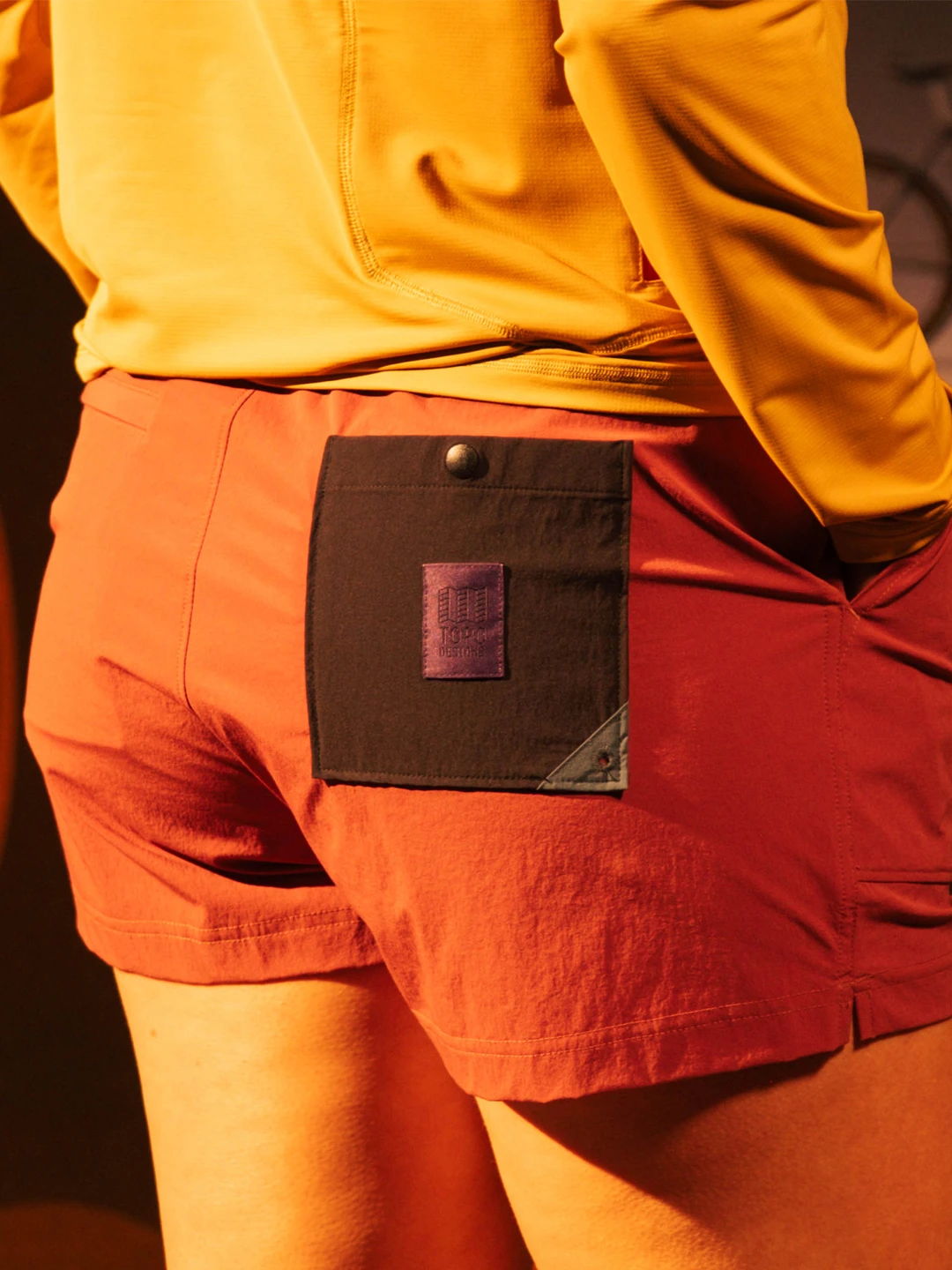 Person wearing maroon shorts with a black pocket, back view.