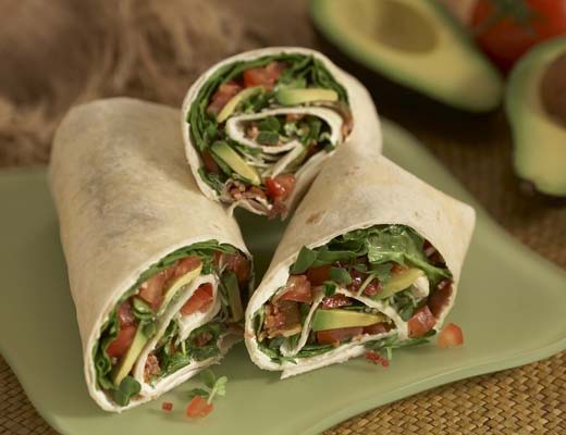 Bacon Lettuce Tomato wraps with avocado wrapped in a tortilla and sliced in half.