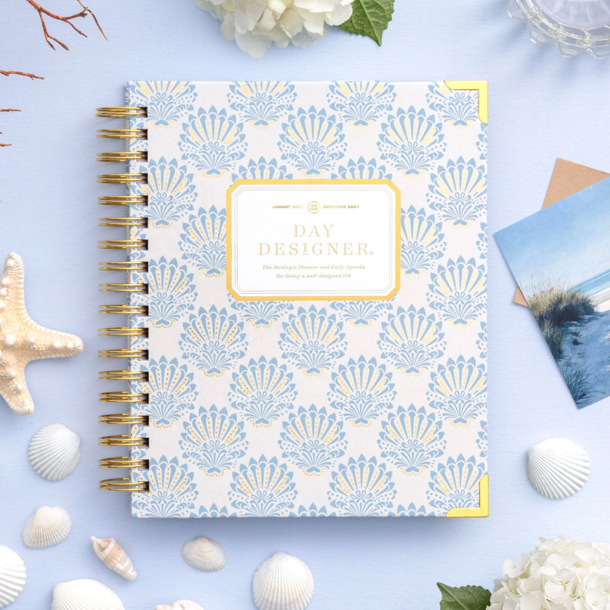 2027 day designer planner featuring blue and gold shells on a light blue background