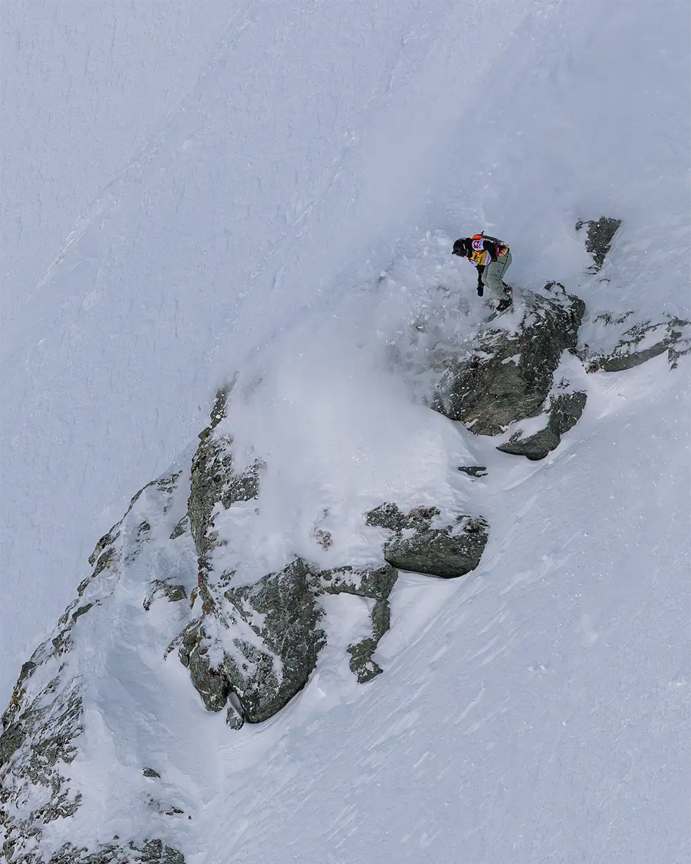 A snowboarder navigating a rocky snow-covered slope.