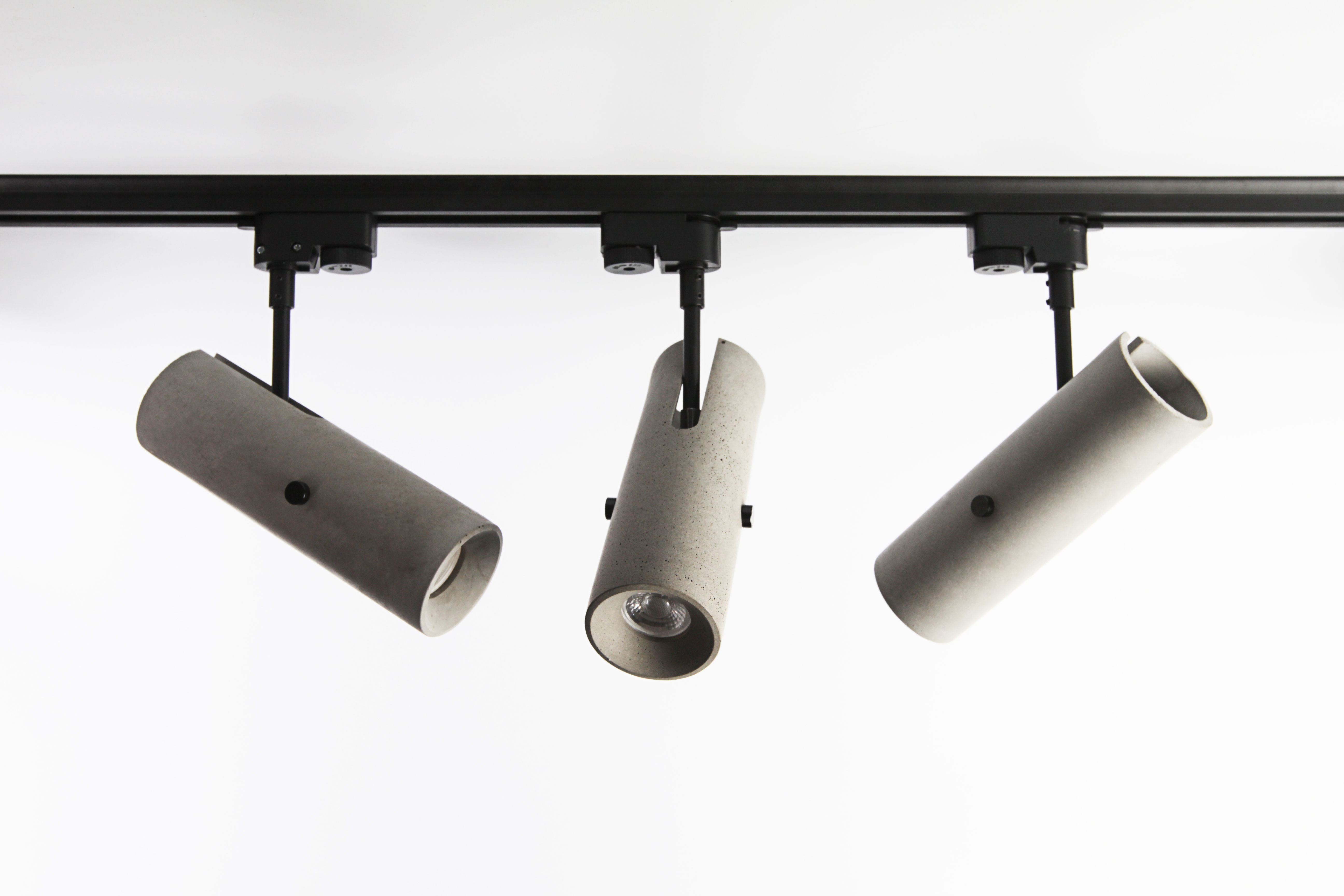 Three concrete light fixtures mounted on a black track