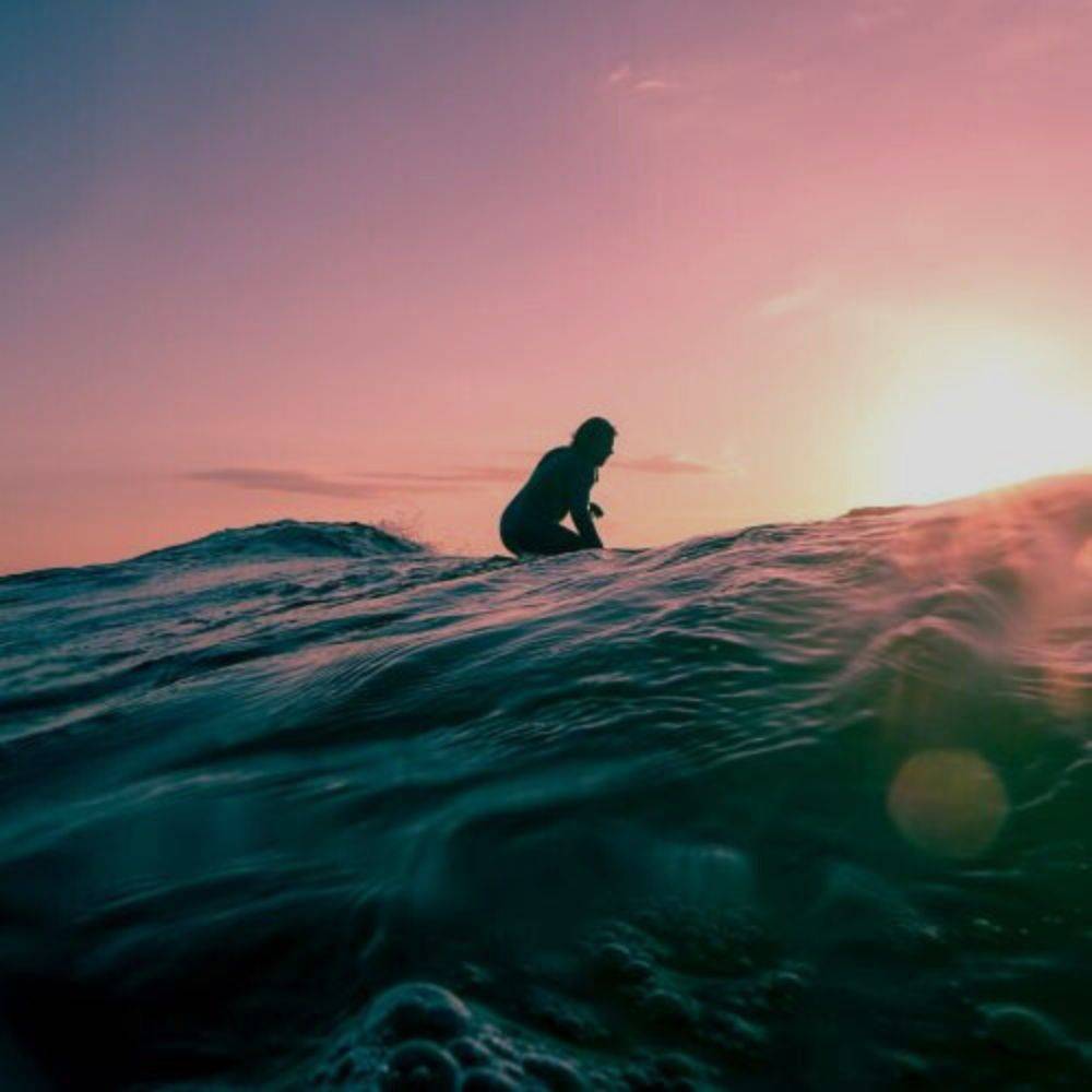 a person surfing on a wave at sunset