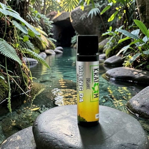 Bottle in a natural setting with water and lush greenery.