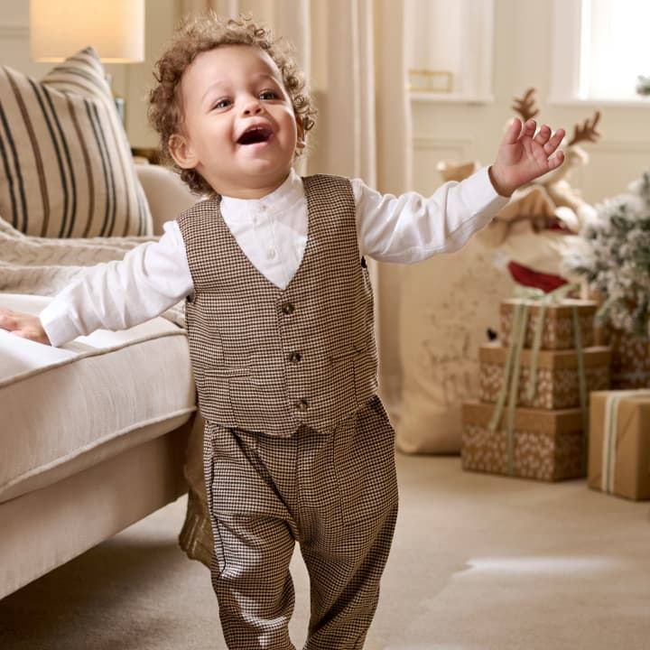 Toddler smiling wearing a waistcoat and trousers