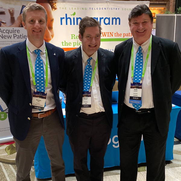 Three men in suits wearing matching custom ties at a tradeshow