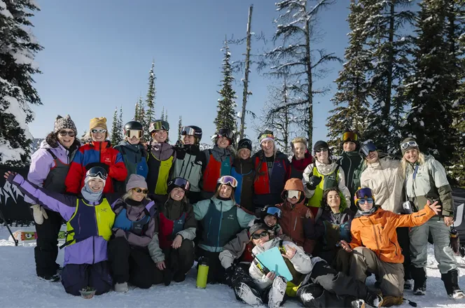 Group photo of snowboarders in winter clothing on a snowy landscape.
