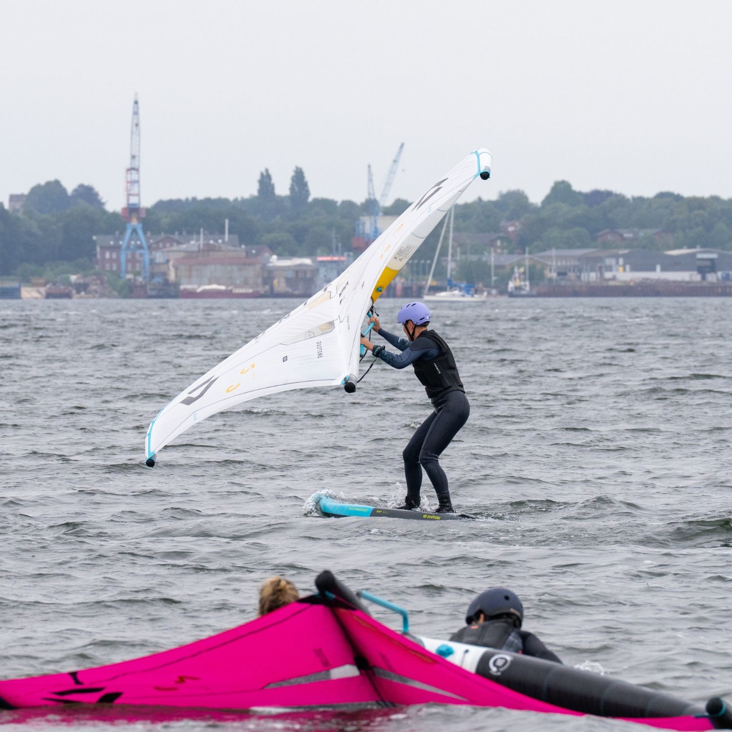 Person wingfoiling on the baltic sea with others in the background.