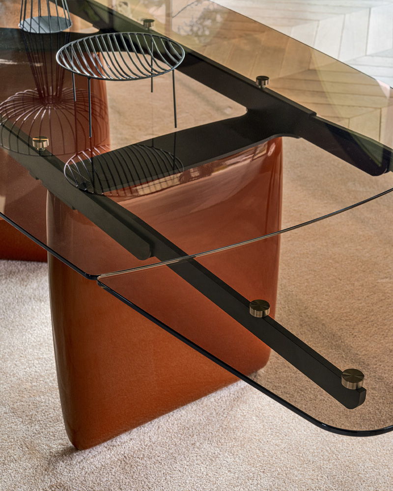 Calligaris glass dining table with brown bases and a metal support structure.