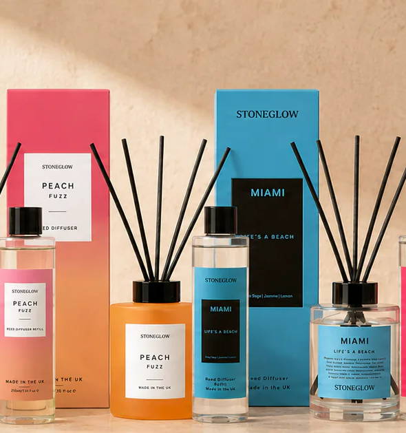 A collection of colorful fragrance bottles and diffusers on a decorative surface.